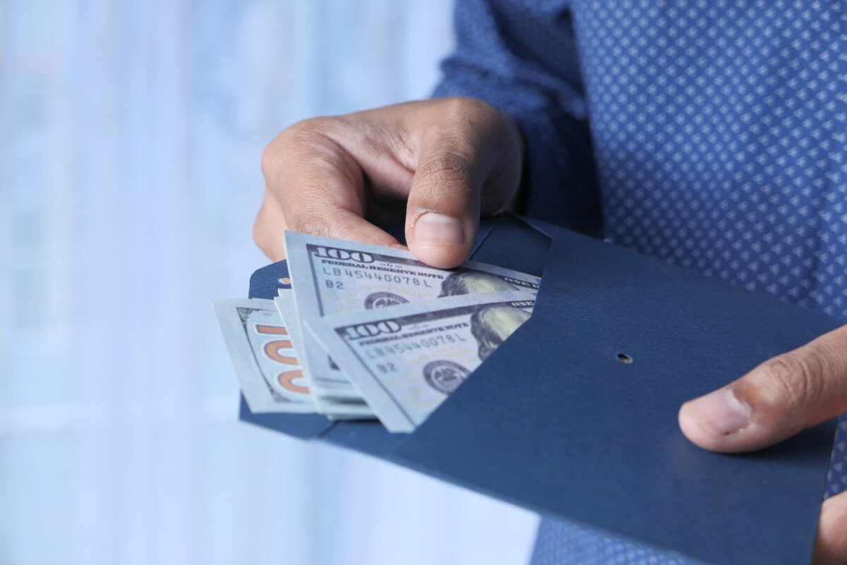 person hand putting cash in a envelope