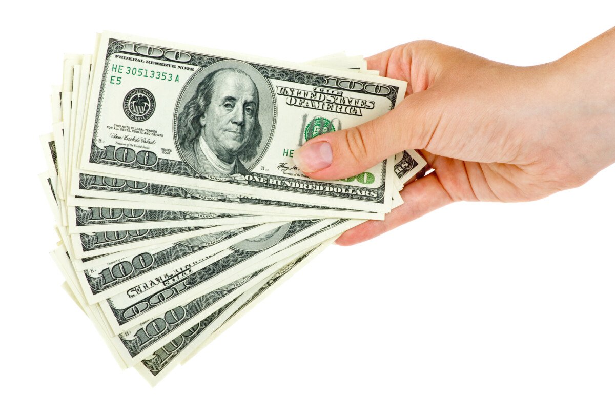 Hand holds bunch of $100 bills isolated on the white background