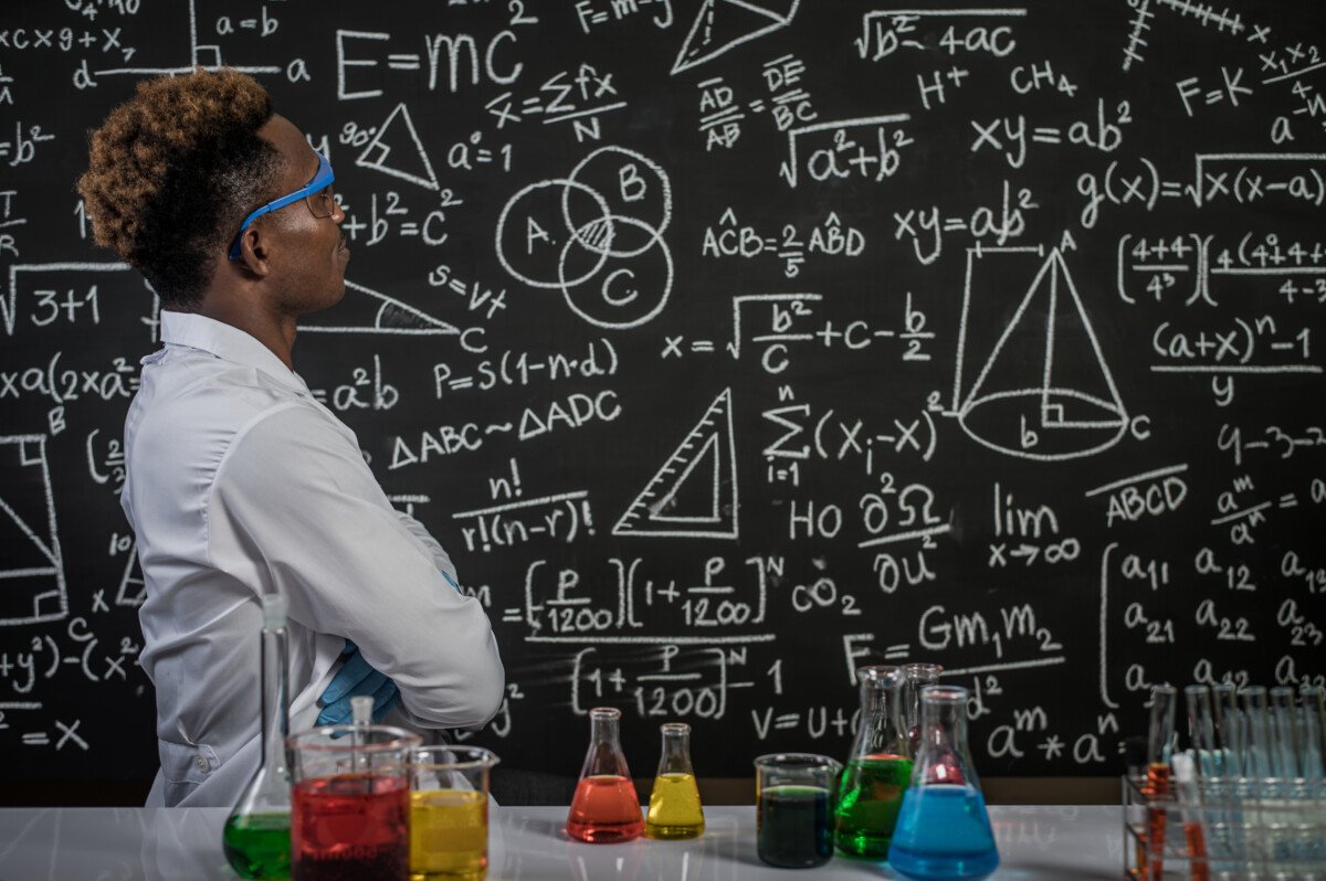 Scientists wear glasses and fold their arms to see the formula on the blackboard in the laboratory.