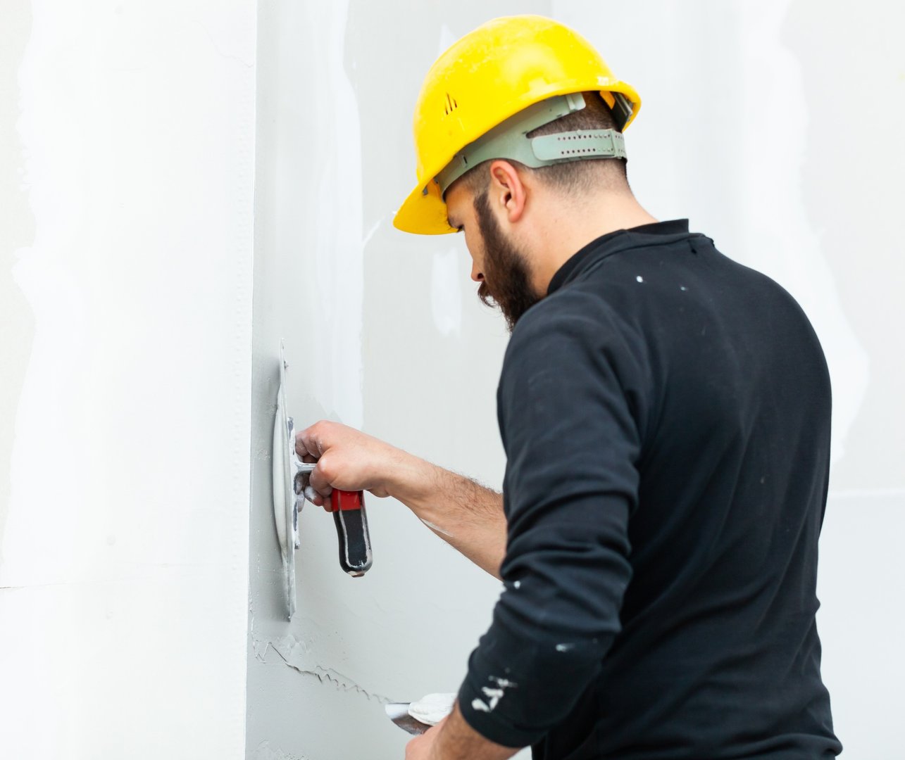 worker plastering gypsum board wall.