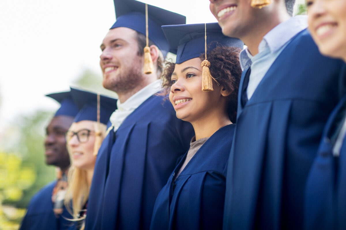 education, graduation and people concept – group of happy international students in mortar boards and bachelor gowns…