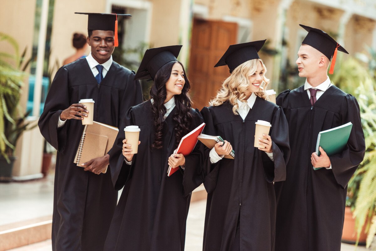 group of graduated multiethnic students with coffee to go and notebooks