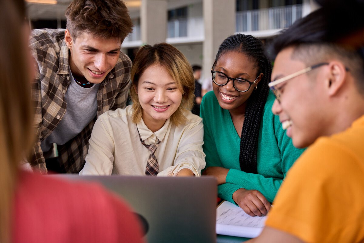 Group of diverse multiethnic smiling young students using laptop studying gathering in classroom. Academics multiracial…