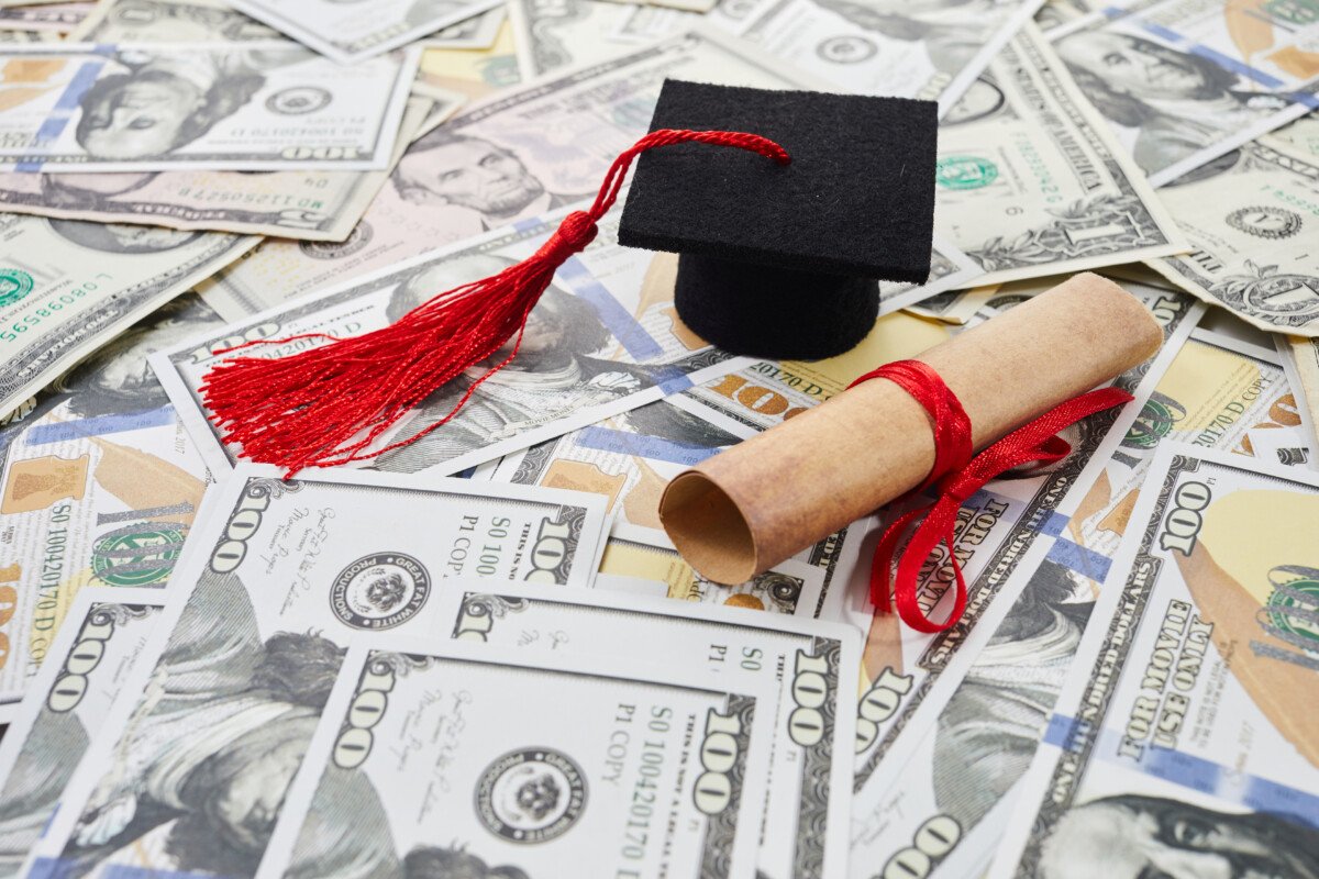 Miniature graduation cap on dollars bills. Student debt crisis.