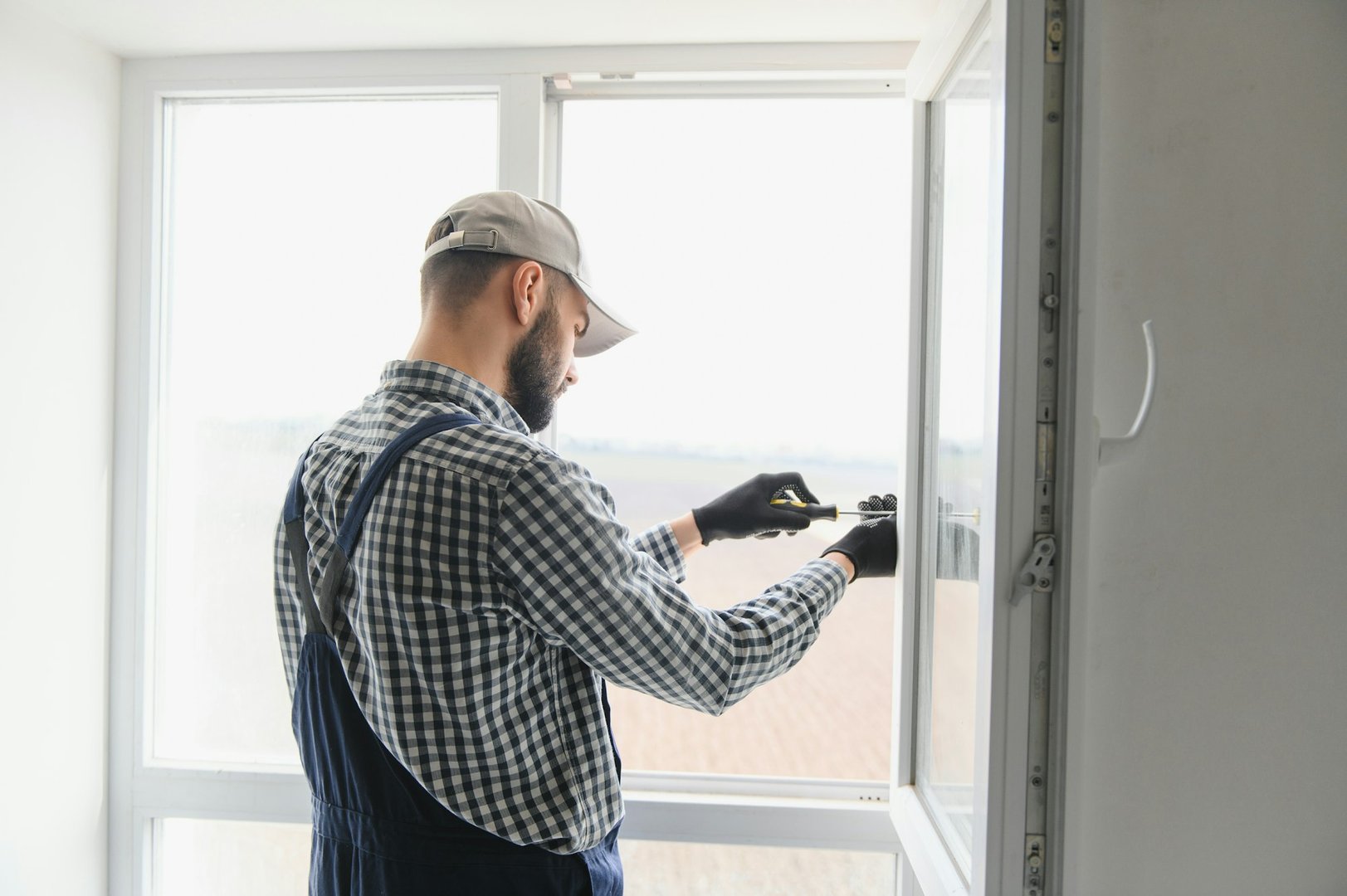 Worker installing plastic window indoors