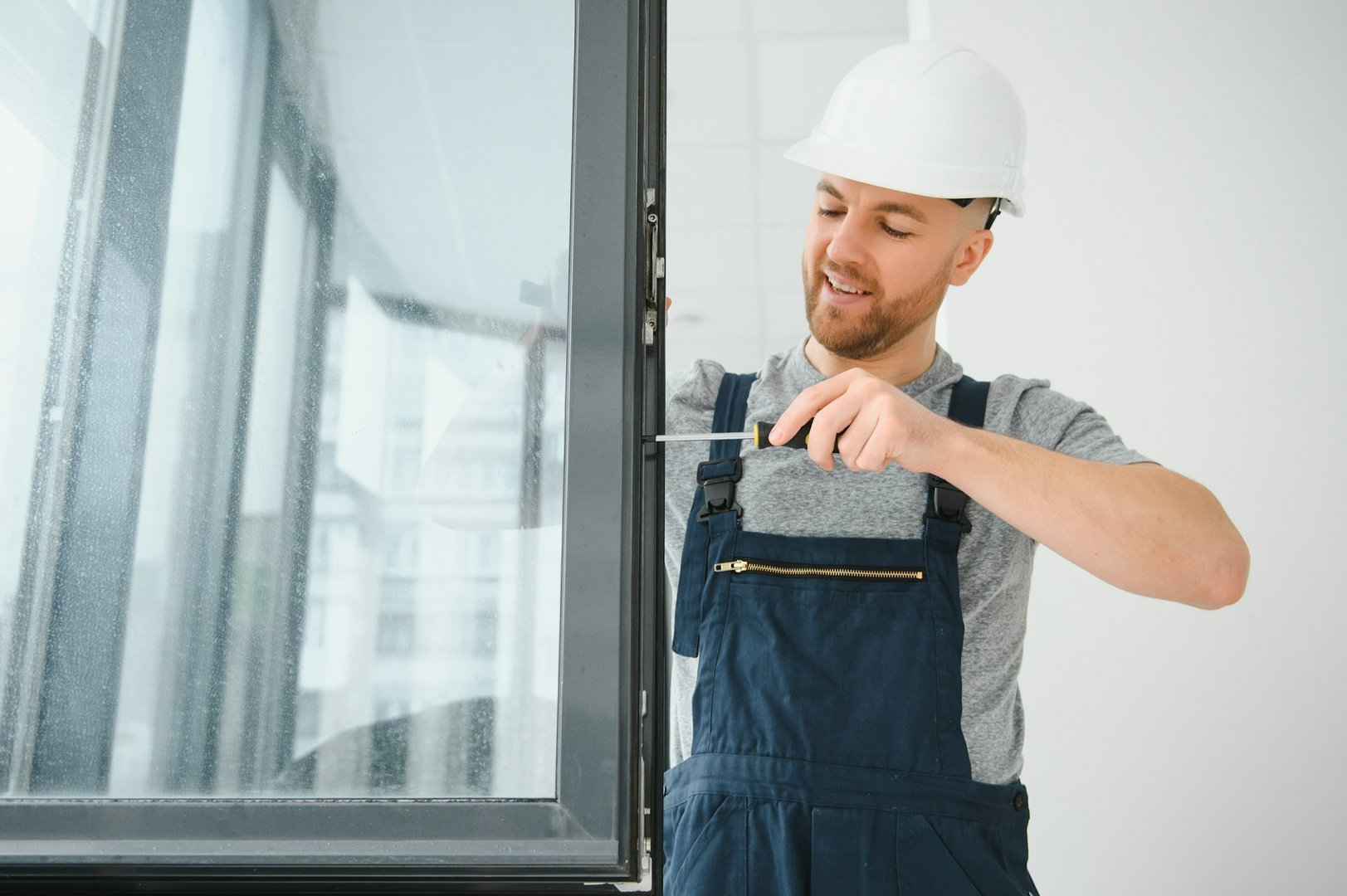 Construction worker repairing plastic window with screwdriver indoors, space for text. Banner design