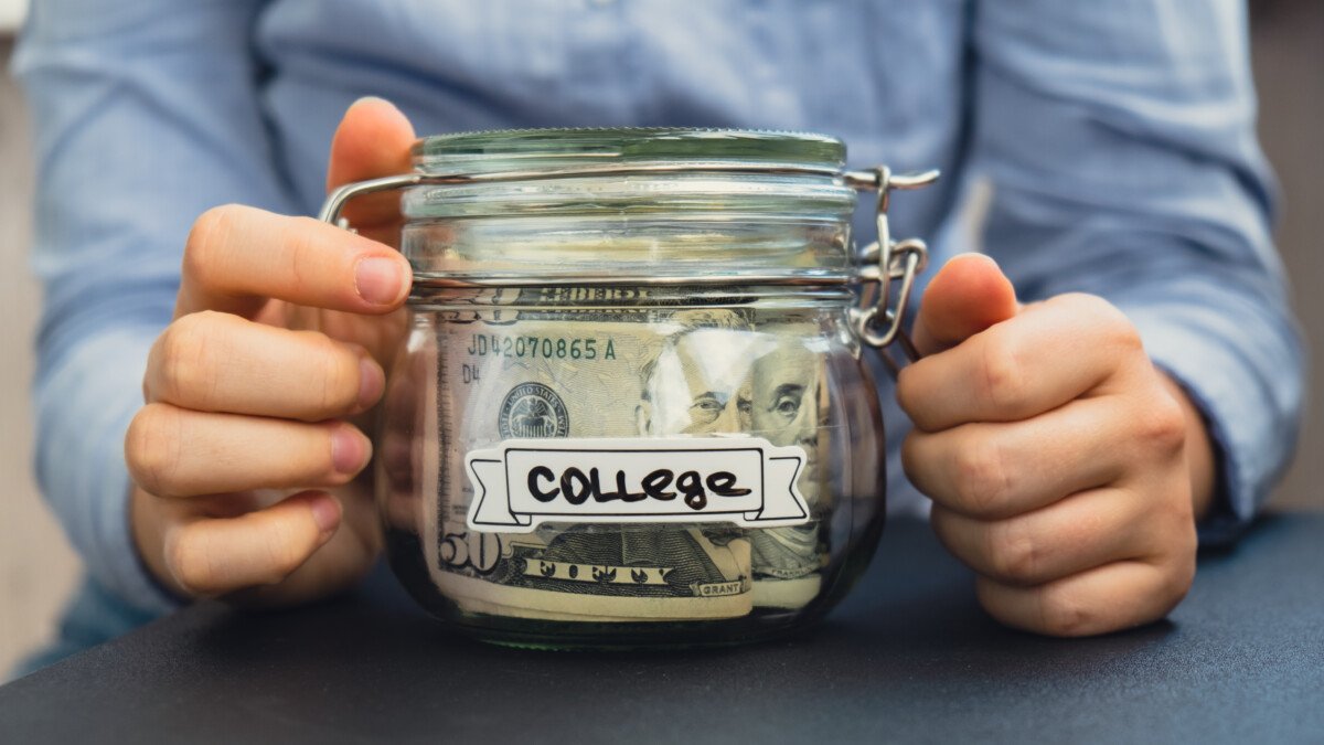 Unrecognizable woman holding Saving Money In Glass Jar filled with Dollars banknotes. COLLEGE transcription in front of…