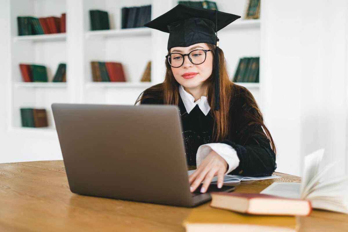 Happy young caucasian woman celebrating college graduation during a video call with friend or family. Online graduation…