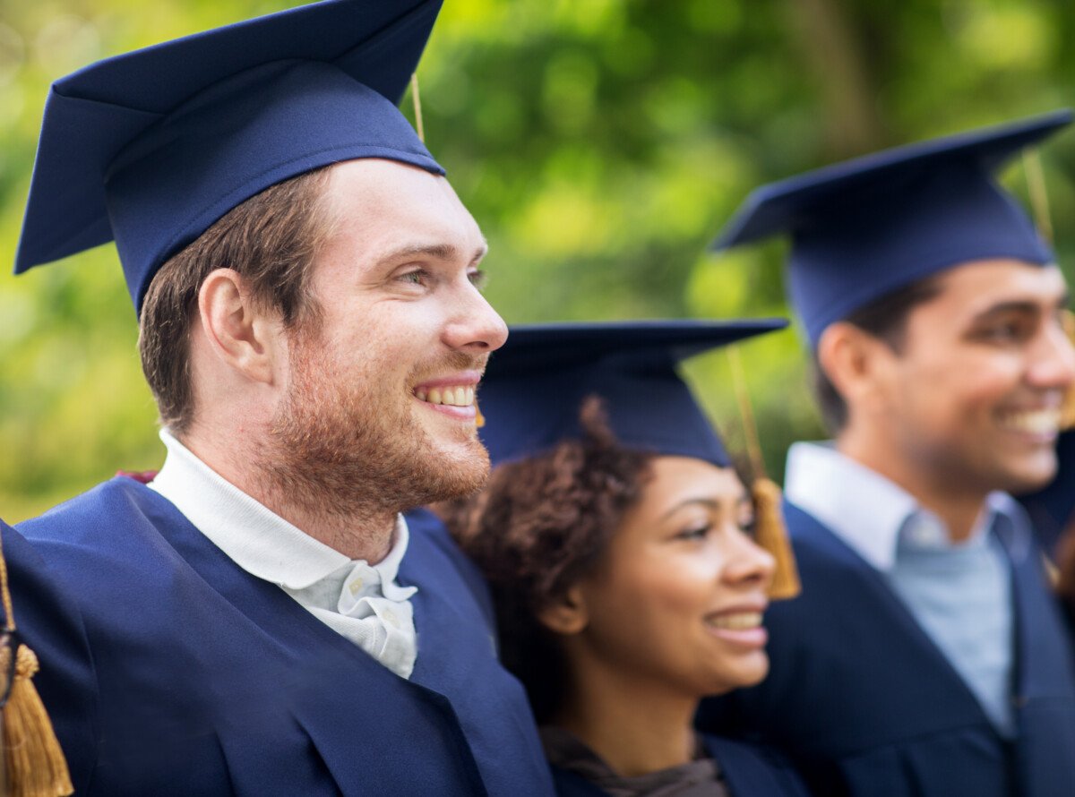 education, graduation and people concept – group of happy international students in mortar boards and bachelor gowns…
