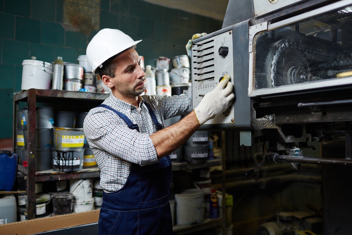 Factory worker in uniform regulating operation system of industrial machine