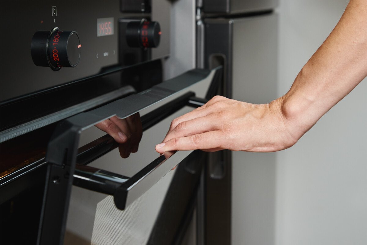 Female hand open electric oven door with handle, Woman using electric oven, Modern household appliances