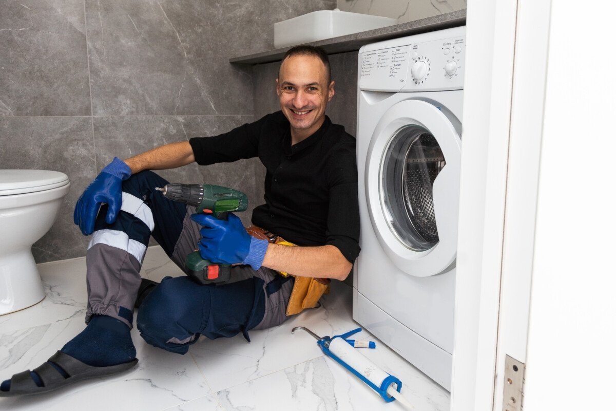 Plumber fixing washing machine on white background. High quality photo