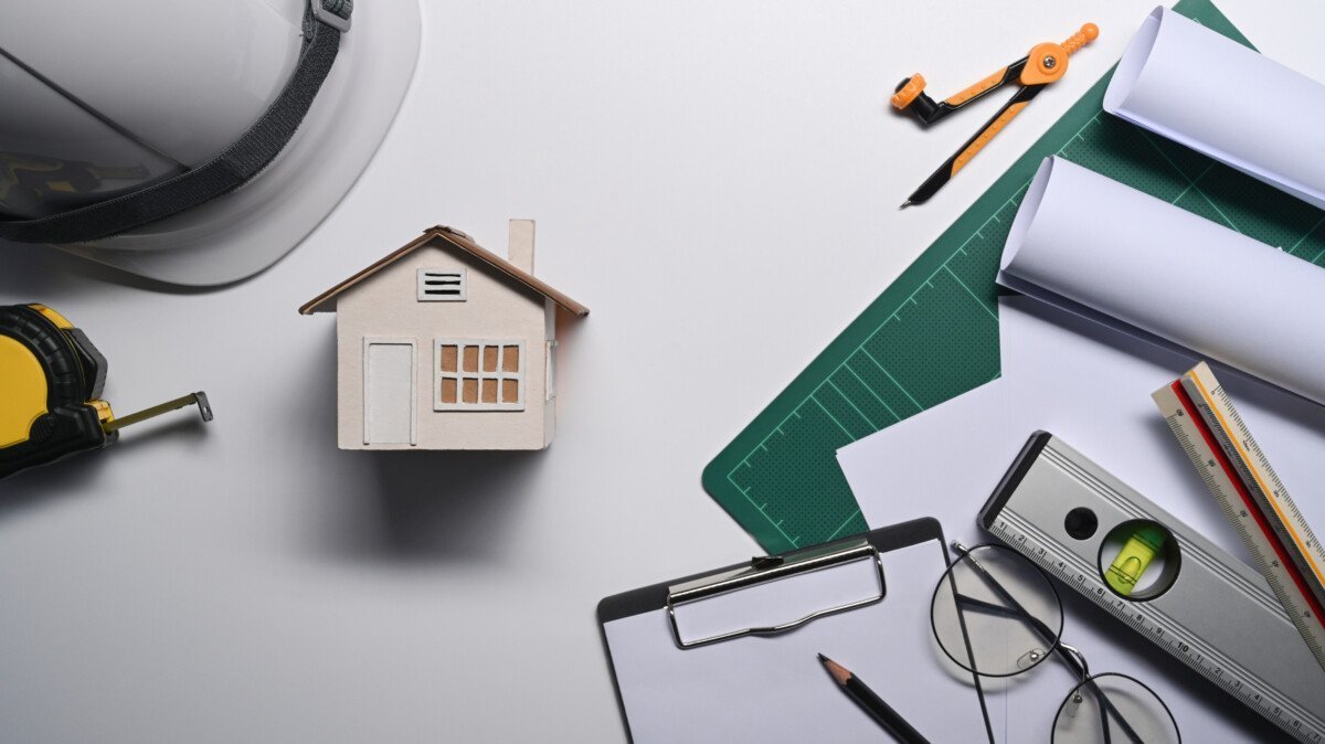 House model, hard hat, blueprints and measurement tape on white background. Real estate, new house concept.