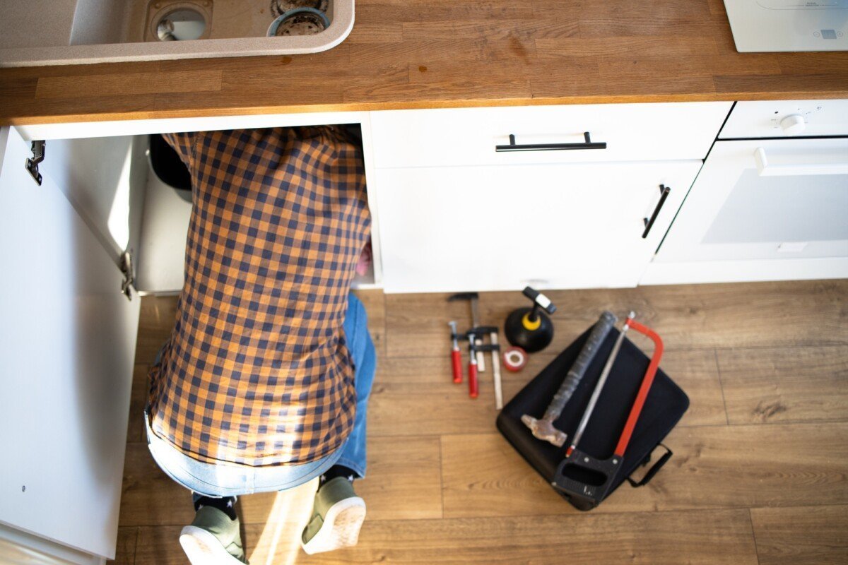 Plumber repairs plumbing pipes in kitchen sink. Removing blockage clog in drain pipe. Replacement of
